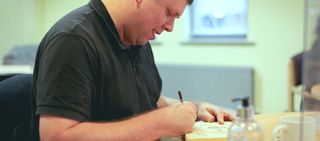 Photo of Second Chance member sat at desk drawing in book.