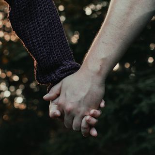 Two people's hands holding one another.